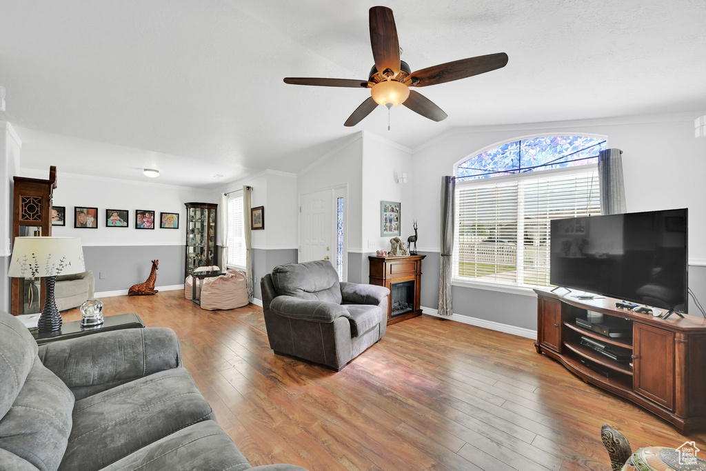 Living room featuring a ceiling fan, lofted ceiling, and light wood finished floors