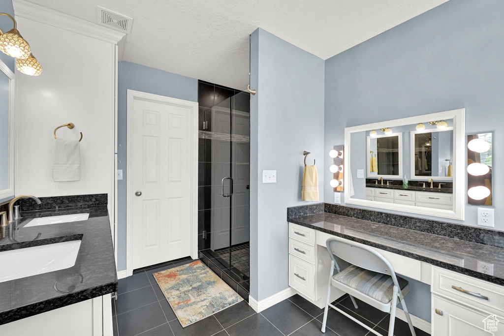 Bathroom featuring double vanity, a shower stall, and tile patterned flooring
