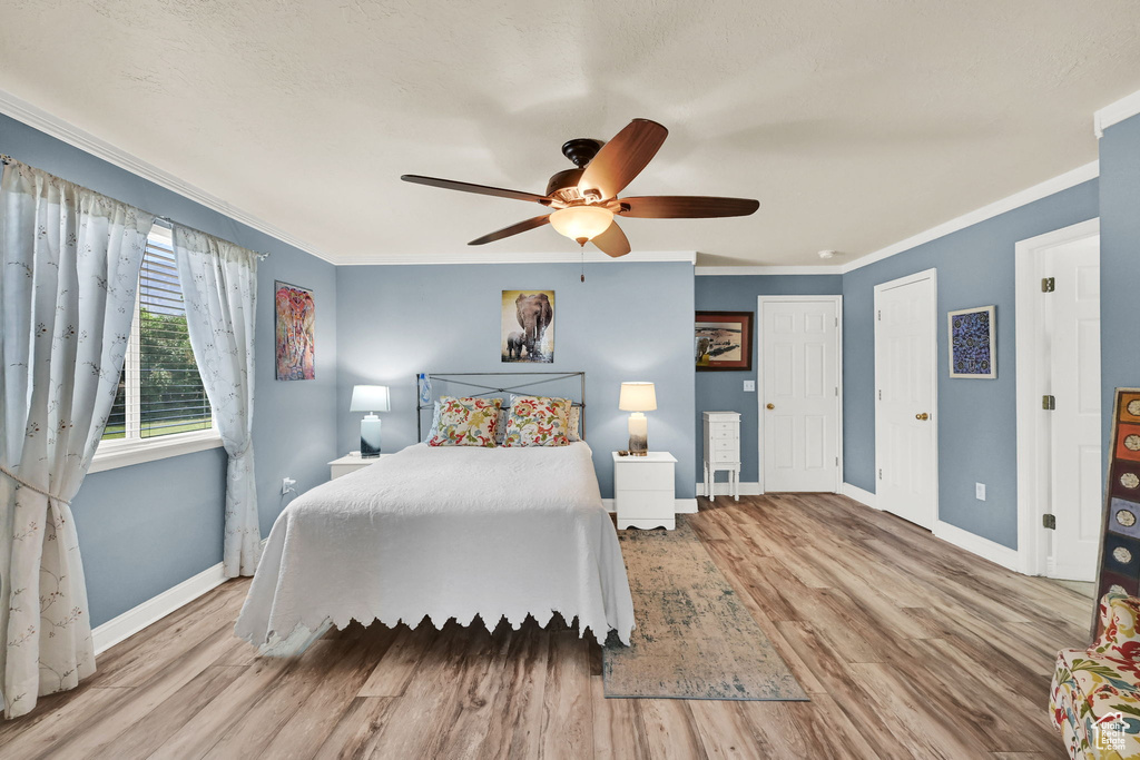 Bedroom featuring crown molding, wood finished floors, and a ceiling fan