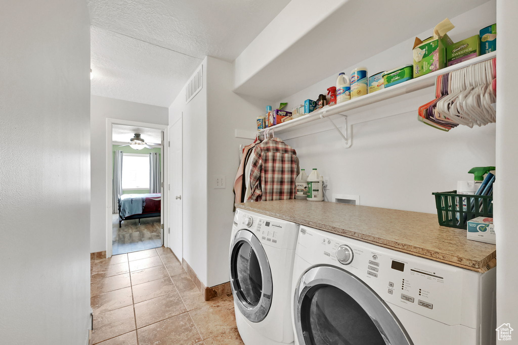 Laundry room featuring separate washer and dryer, a textured ceiling, a ceiling fan, and light tile patterned floors