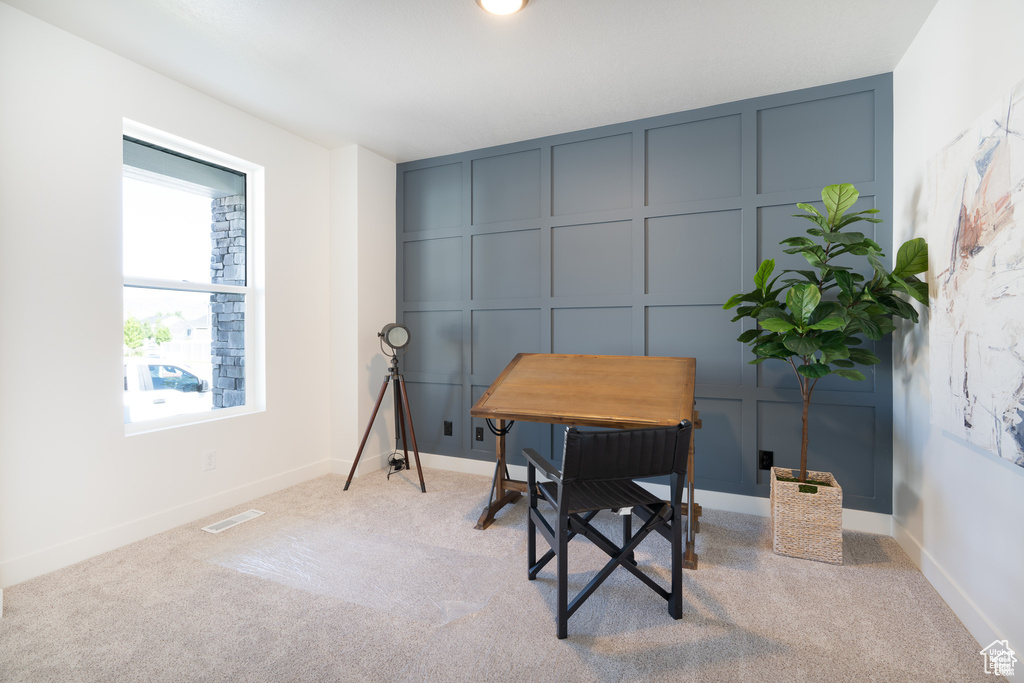 Office area with a decorative wall and light carpet