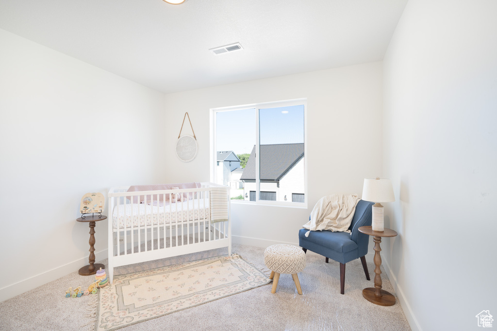 Carpeted bedroom with baseboards and a crib