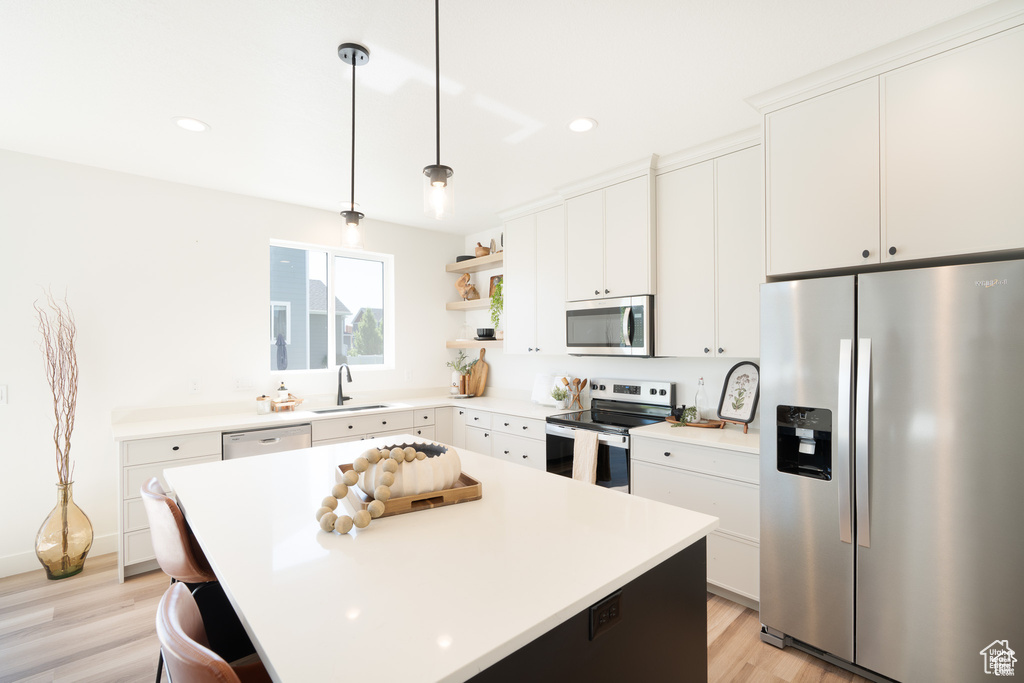 Kitchen featuring stainless steel appliances, open shelves, light wood-style flooring, light countertops, and recessed lighting