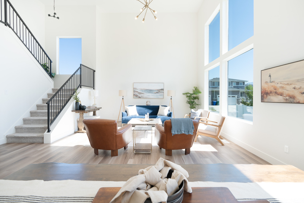Living room with a towering ceiling, stairs, a chandelier, and wood finished floors