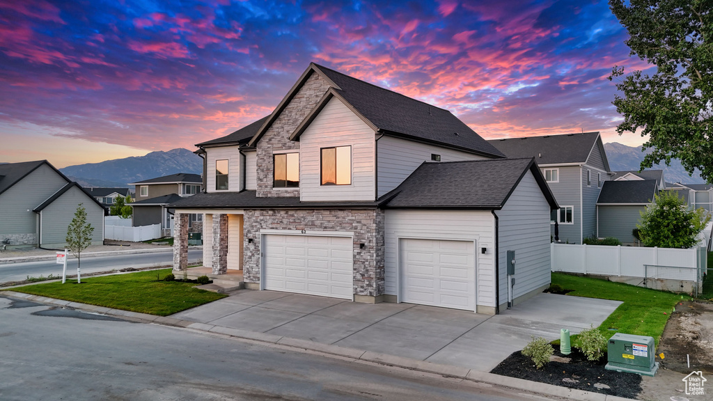 View of front of house featuring stone siding, driveway, a mountain view, a shingled roof, and a garage