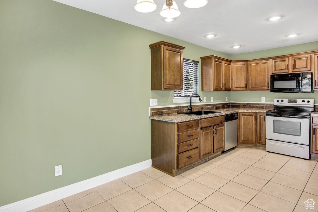 Kitchen with stainless steel appliances, light tile patterned flooring, brown cabinets, and recessed lighting