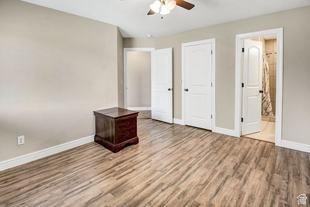 Unfurnished bedroom with wood finished floors, ensuite bathroom, and a ceiling fan