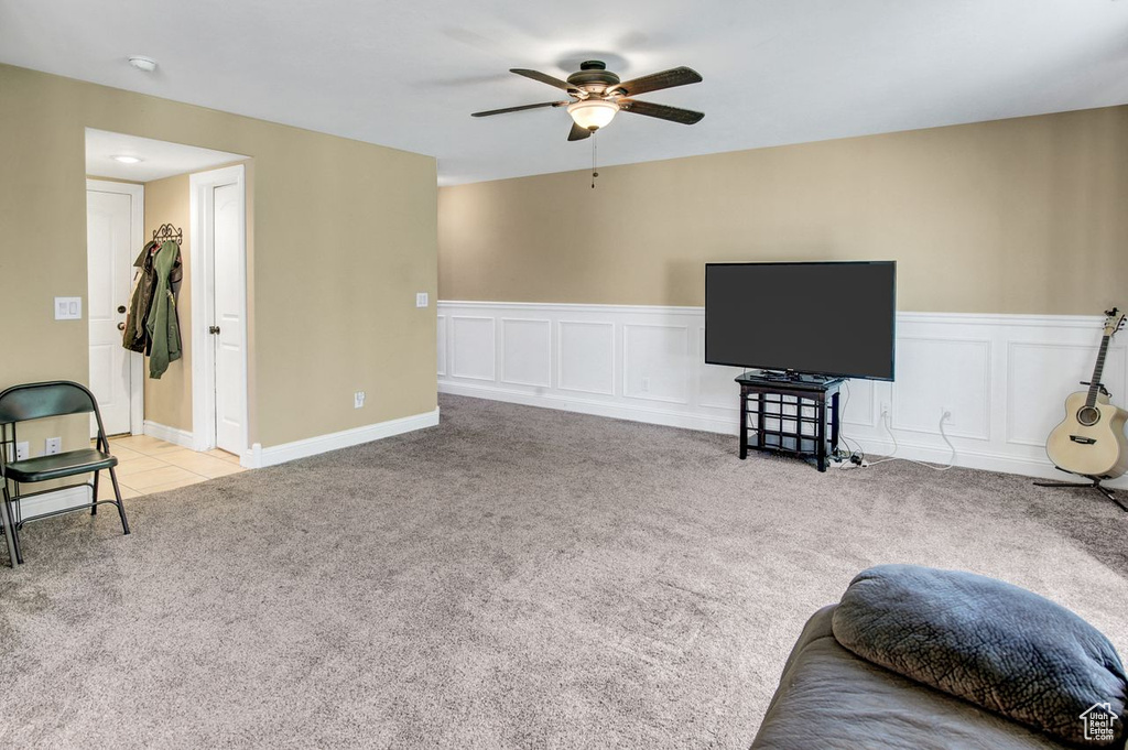 Carpeted living area featuring ceiling fan and wainscoting