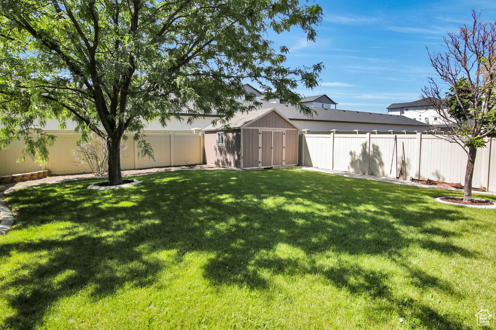 Fenced backyard featuring a shed