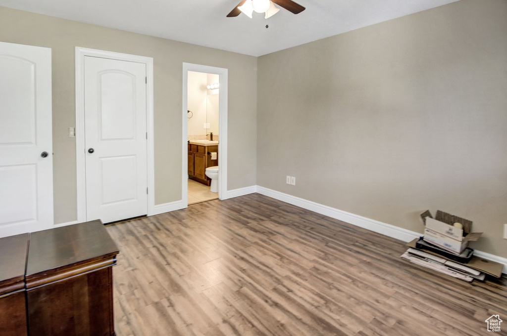 Unfurnished bedroom featuring wood finished floors, ensuite bath, and ceiling fan