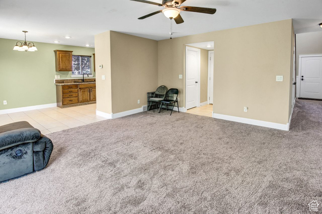 Living room with ceiling fan, recessed lighting, light colored carpet, light tile patterned flooring, and a chandelier