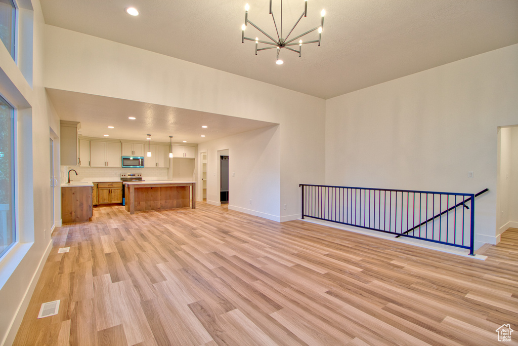 Unfurnished living room featuring a chandelier, light wood finished floors, and recessed lighting