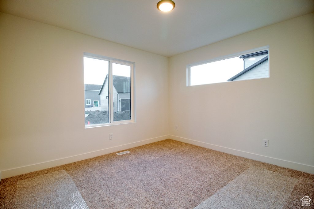 Spare room featuring healthy amount of natural light and light colored carpet