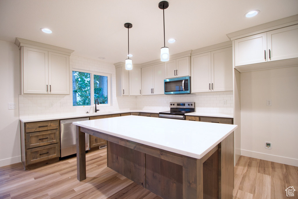 Kitchen with stainless steel appliances, backsplash, light wood-style floors, light countertops, and recessed lighting