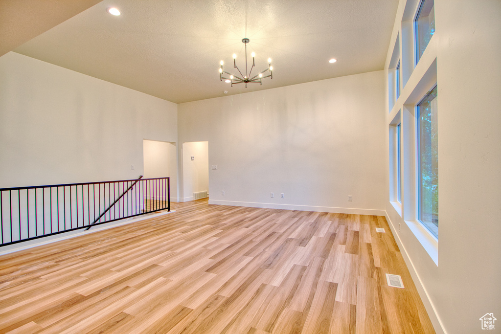 Spare room with a chandelier, light wood-style flooring, and recessed lighting