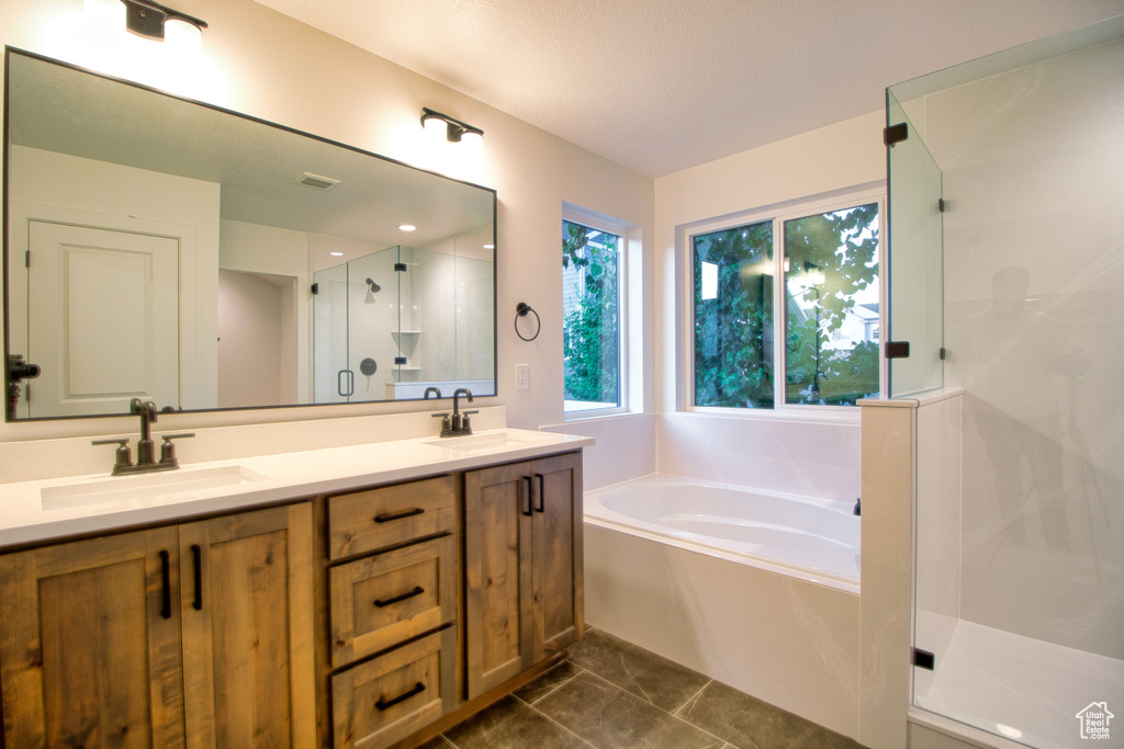 Full bathroom with a stall shower, a bath, and double vanity