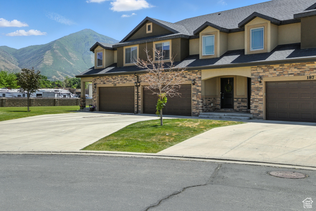 View of front facade with a garage, a mountain view, stucco siding, driveway, and stone siding