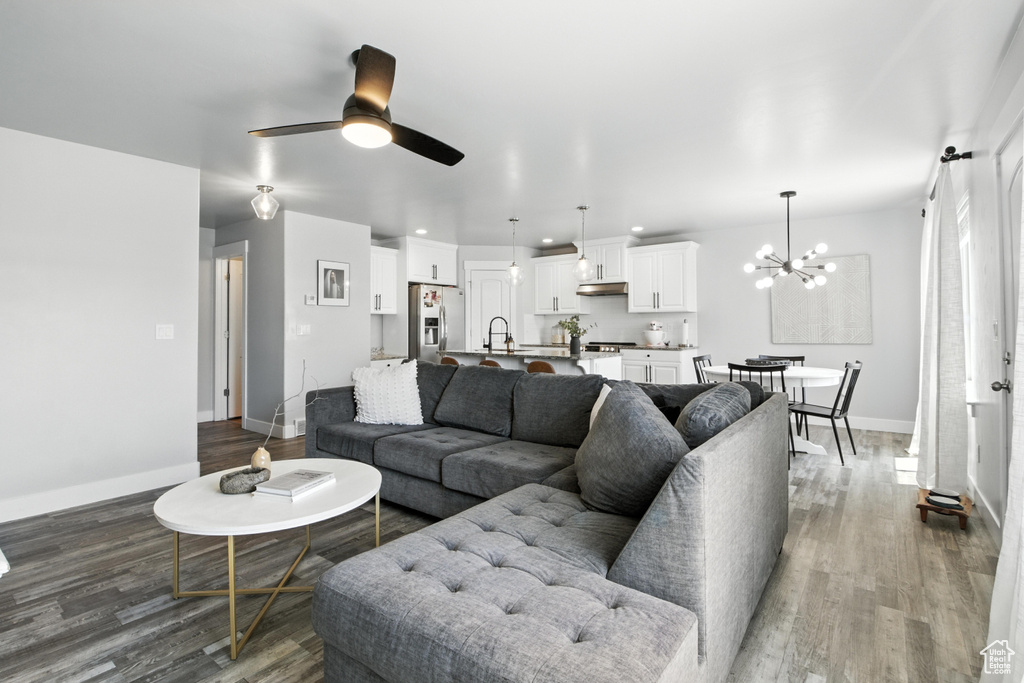 Living room featuring wood finished floors, a chandelier, a ceiling fan, and recessed lighting