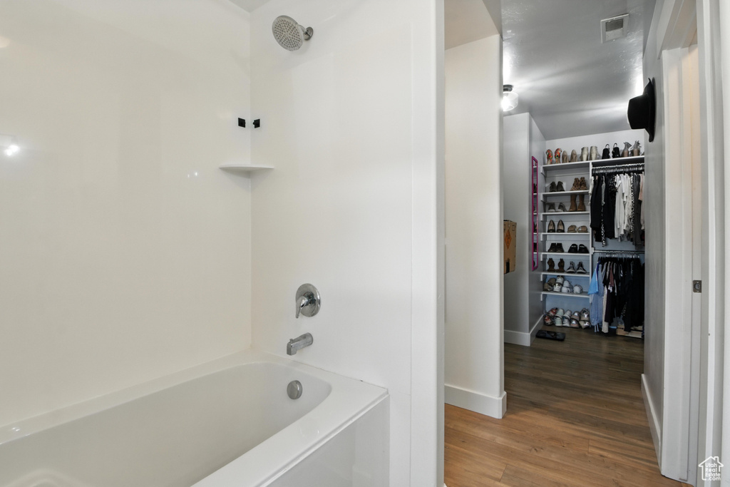 Full bath with wood finished floors, shower / bathtub combination, and a spacious closet