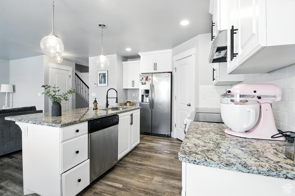 Kitchen featuring stainless steel appliances, extractor fan, dark wood-style floors, an island with sink, and white cabinets