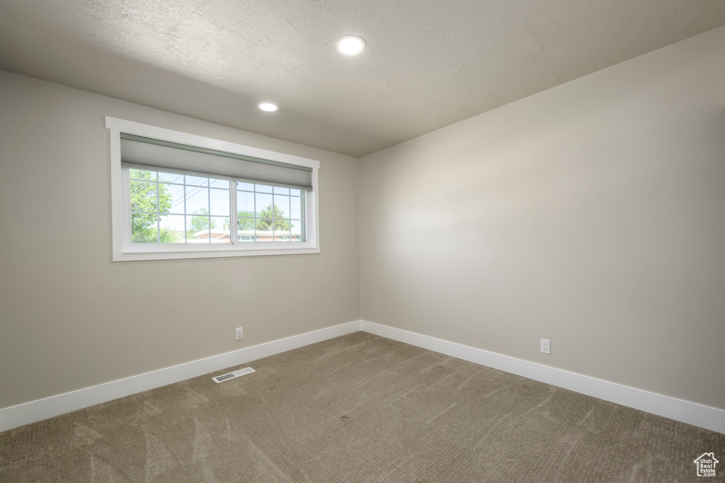 Carpeted empty room with recessed lighting and a textured ceiling