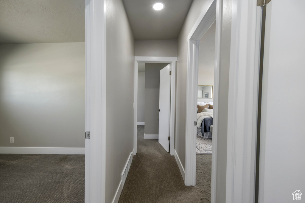 Hallway featuring dark carpet and baseboards