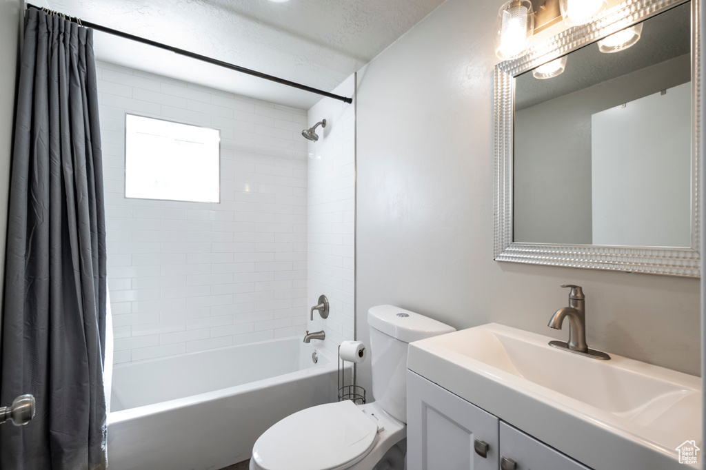 Full bathroom featuring shower / bathtub combination with curtain, vanity, and a textured ceiling