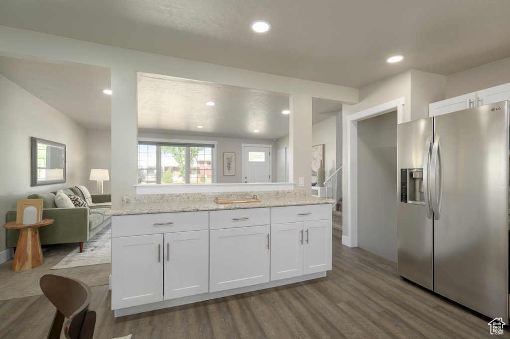 Kitchen with stainless steel fridge with ice dispenser, white cabinetry, dark wood-type flooring, recessed lighting, and open floor plan
