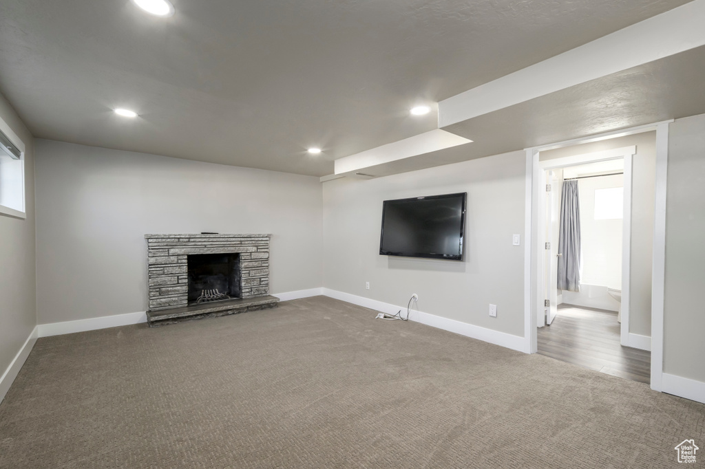 Unfurnished living room with carpet floors, recessed lighting, and a stone fireplace