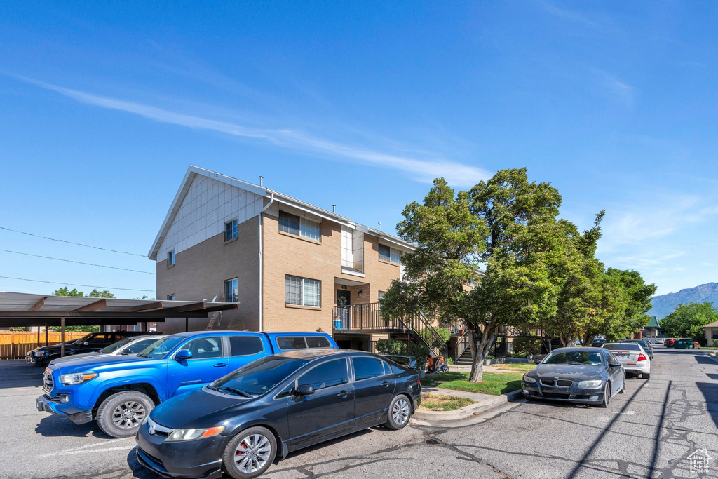 View of property featuring uncovered parking, a mountain view, and stucco siding