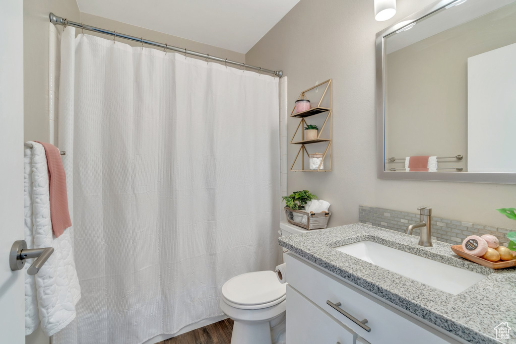 Full bath with vanity, decorative backsplash, wood finished floors, and a shower with shower curtain