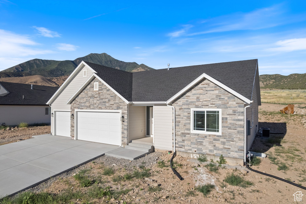 Craftsman house featuring stone siding, concrete driveway, a garage, and a mountain view