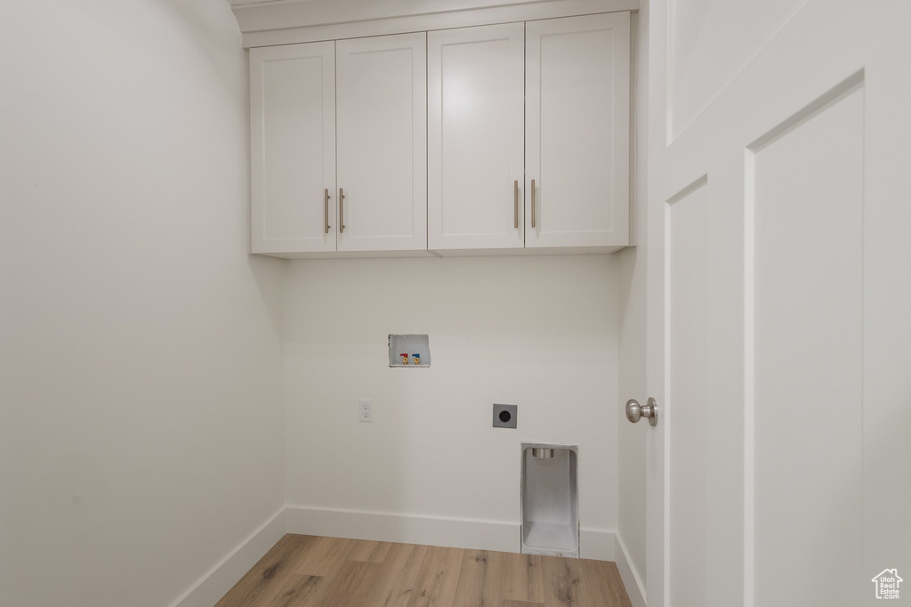 Washroom with hookup for a washing machine, hookup for an electric dryer, light wood-style flooring, and cabinet space