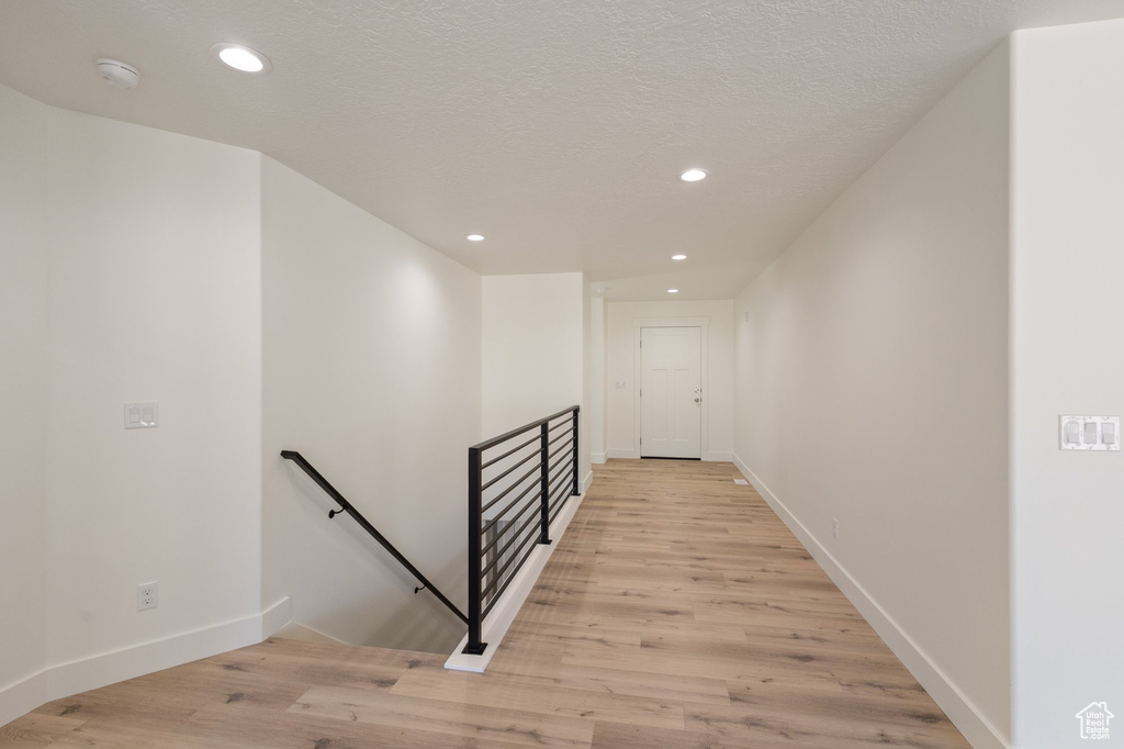 Corridor featuring an upstairs landing, light wood-style floors, and recessed lighting