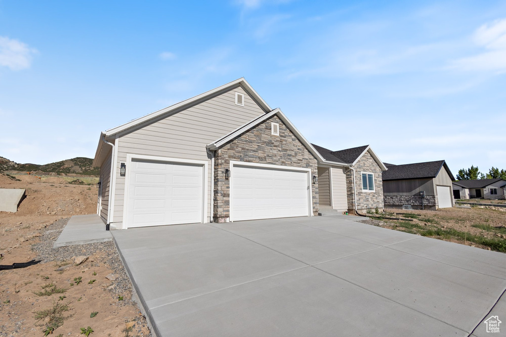 View of front of house featuring stone siding, an attached garage, and driveway