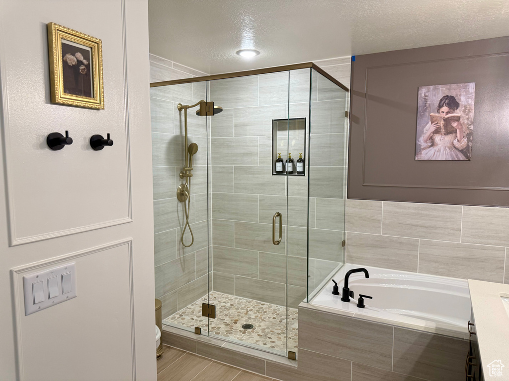Bathroom featuring a shower stall, a garden tub, and a textured ceiling