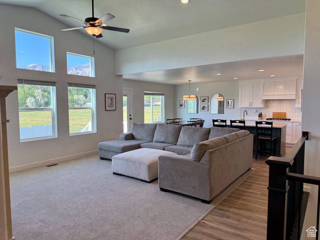 Living area featuring a ceiling fan, light wood-style floors, recessed lighting, and high vaulted ceiling