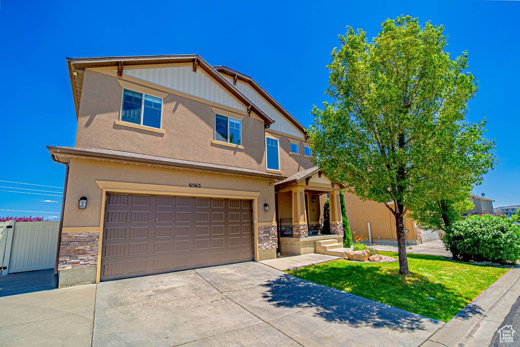 Craftsman inspired home featuring stone siding, a garage, driveway, stucco siding, and a front yard