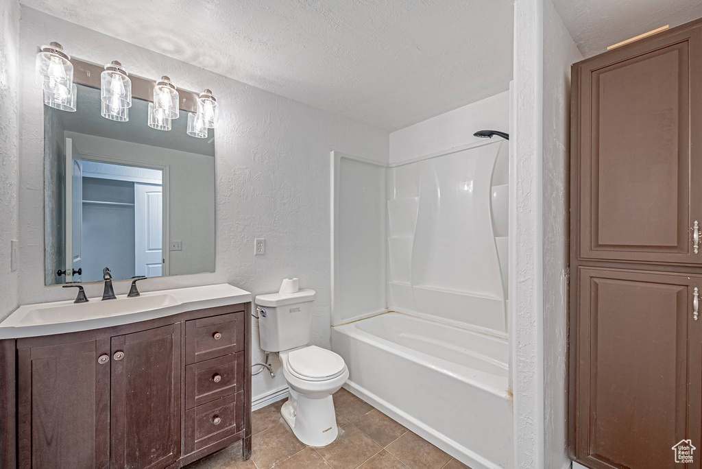 Bathroom with a textured wall, vanity, a textured ceiling, bathing tub / shower combination, and tile patterned floors