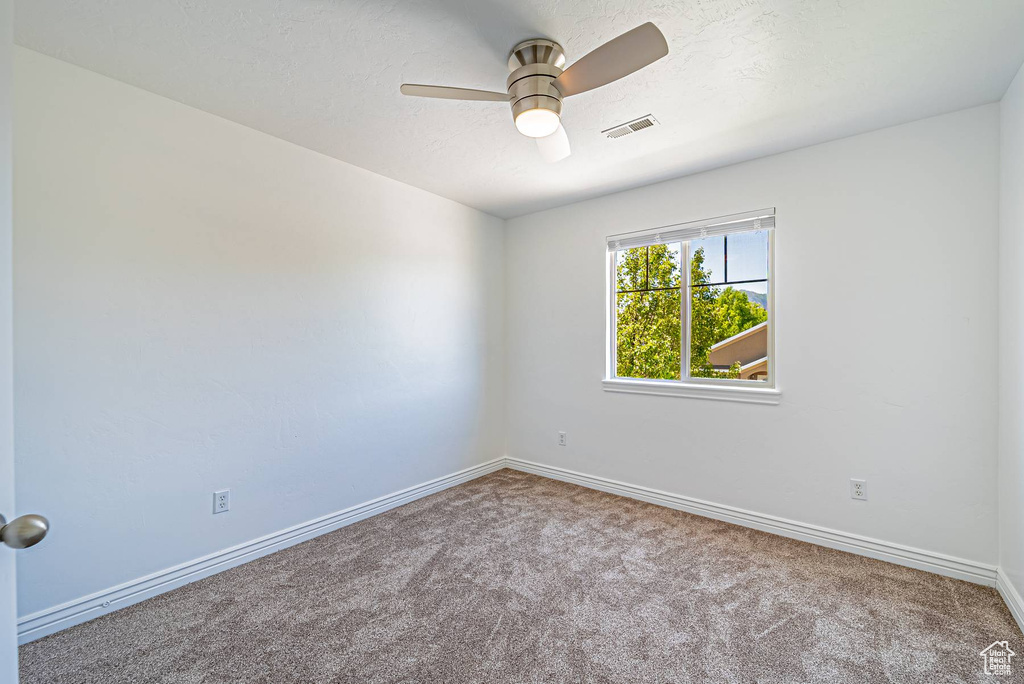 Carpeted empty room with a ceiling fan and baseboards