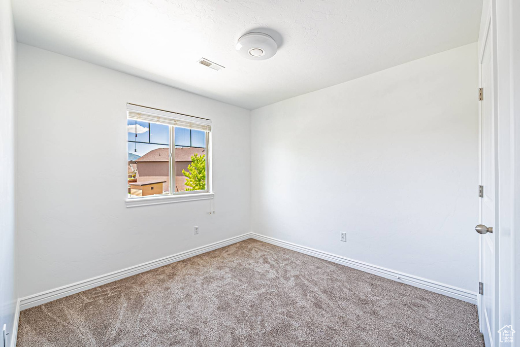 Carpeted spare room featuring baseboards