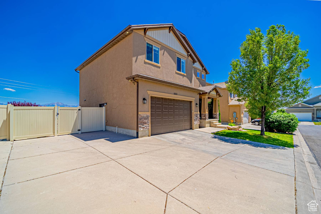 View of front of house featuring a gate, concrete driveway, a garage, stucco siding, and stone siding