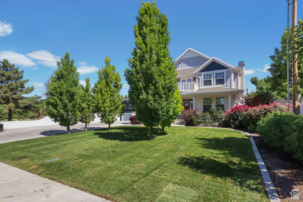 View of front of property with a chimney, a front lawn, and a balcony