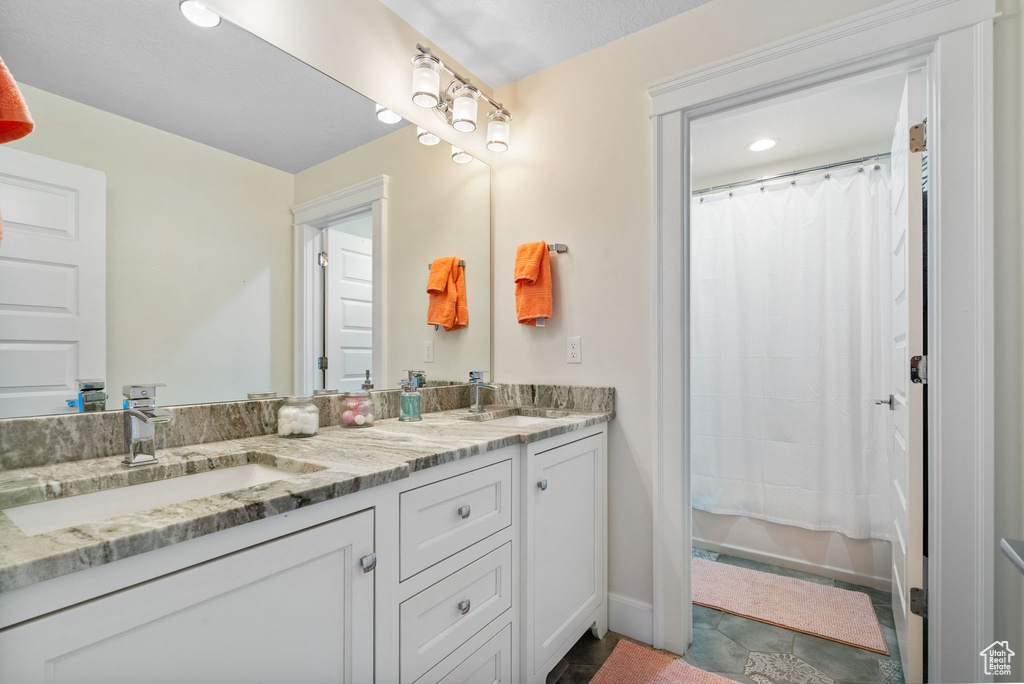 Full bathroom featuring double vanity and curtained shower