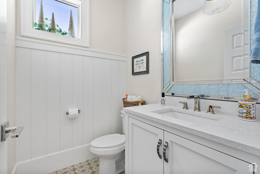 Bathroom with vanity, wainscoting, and a decorative wall