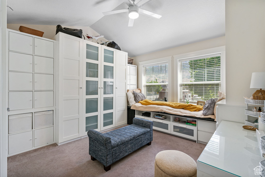 Bedroom with light colored carpet, vaulted ceiling, and a ceiling fan