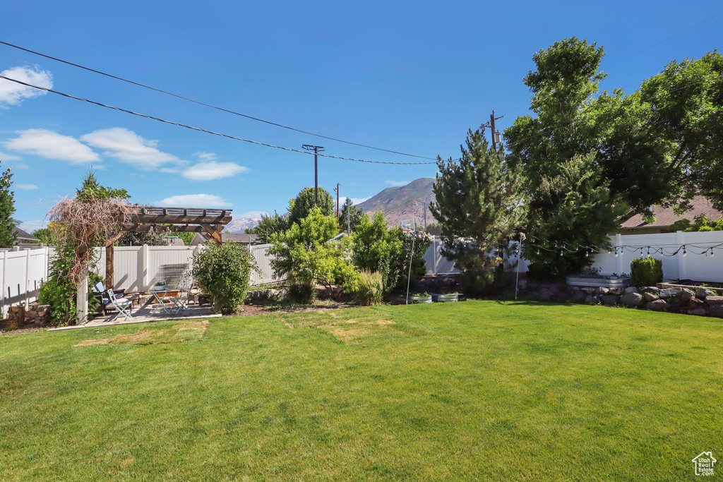Fenced backyard with a pergola, a mountain view, and a patio