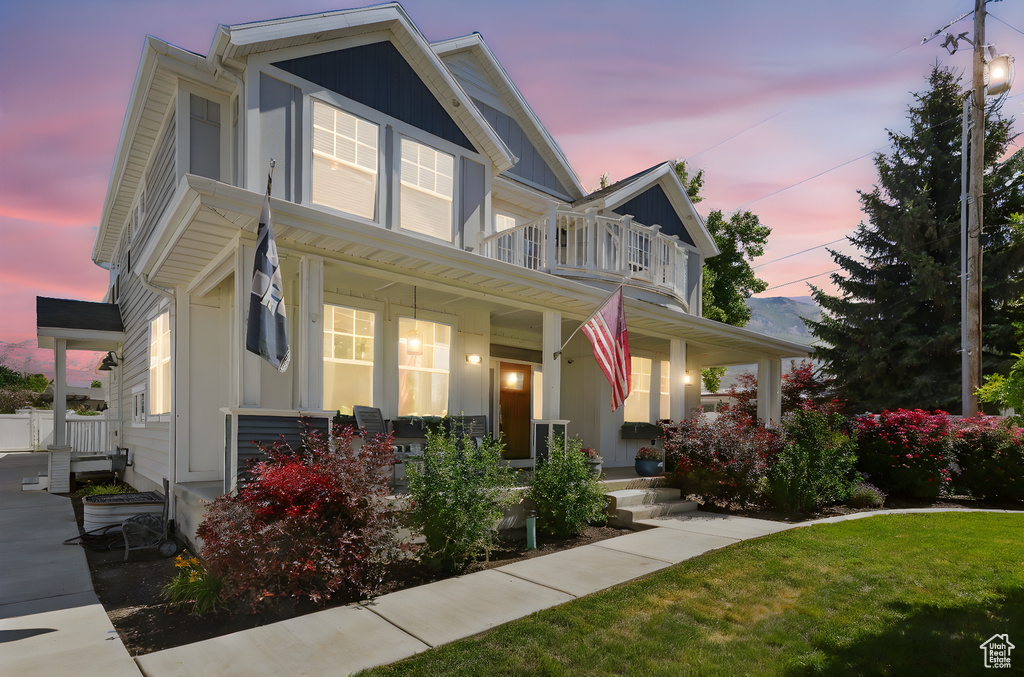 View of front of house with a porch, a balcony, and a front lawn