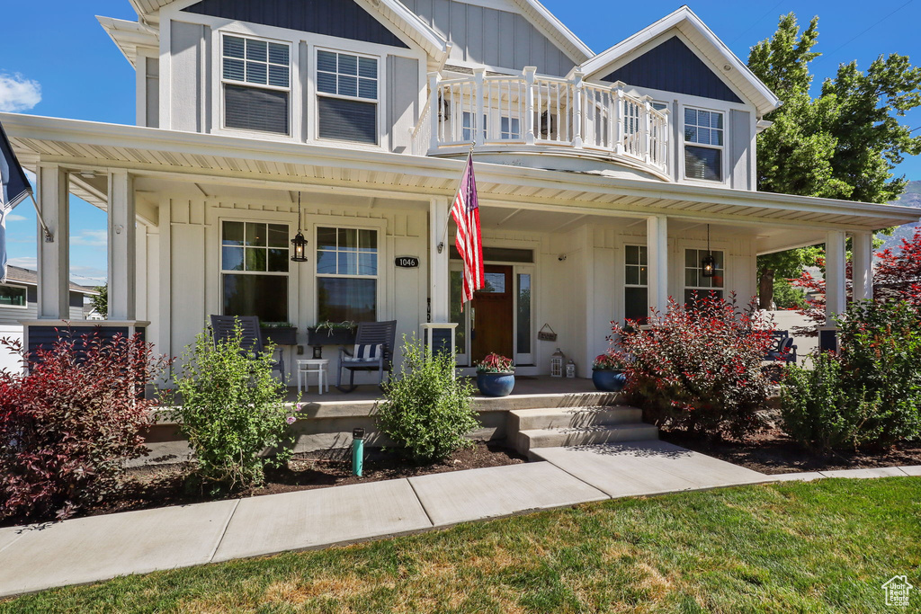 View of front facade with a porch, a balcony, and board and batten siding