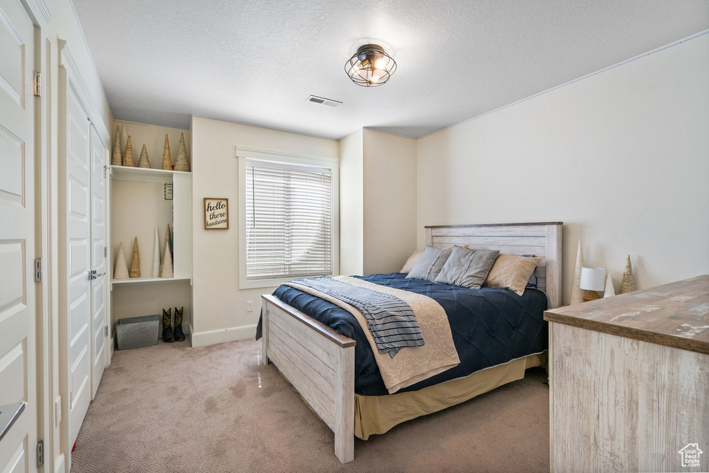 Bedroom featuring light colored carpet and a textured ceiling